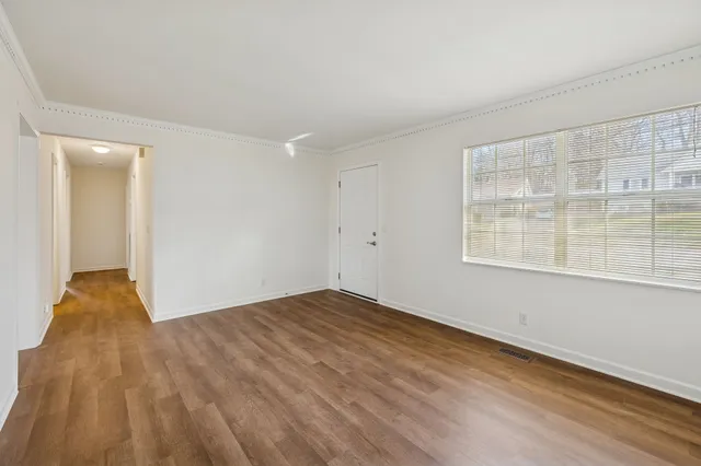 a view of an empty room with wooden floor and a window