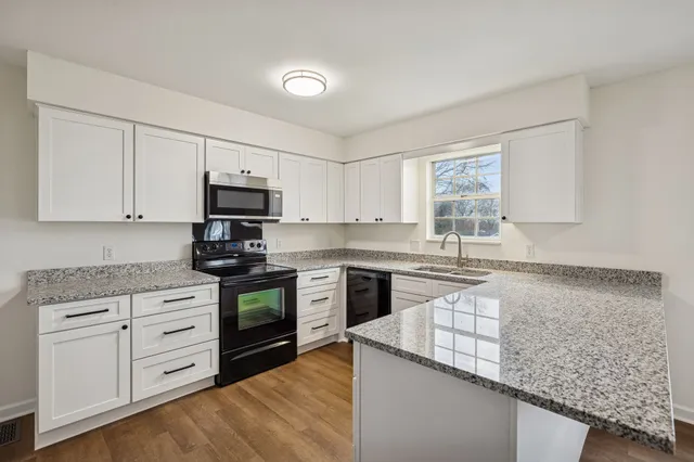 a kitchen with granite countertop white cabinets and stainless steel appliances