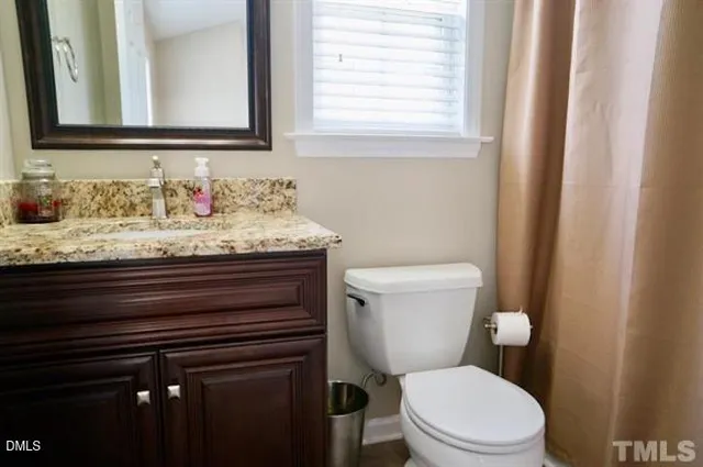 a bathroom with a granite countertop toilet sink and mirror