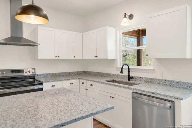 a kitchen with granite countertop a sink a stove and cabinets