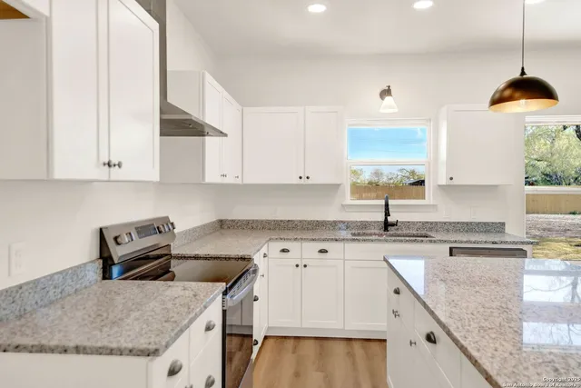a kitchen with granite countertop a sink a stove and cabinets