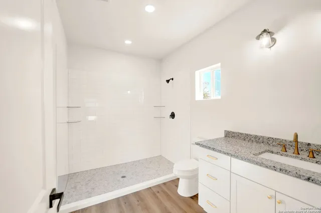 a bathroom with a granite countertop sink toilet and shower