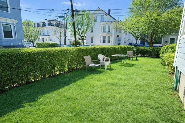 a view of backyard with table and chairs and potted plants
