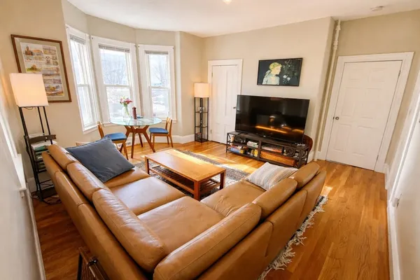 a living room with furniture a flat screen tv and a window