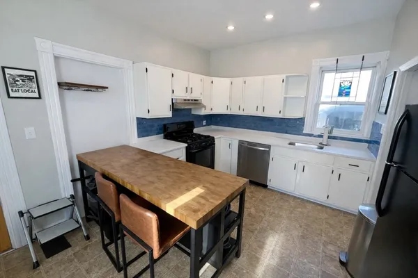 a kitchen with a sink a stove a refrigerator and white cabinets