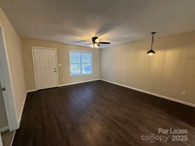 an empty room with wooden floor ceiling fan and windows