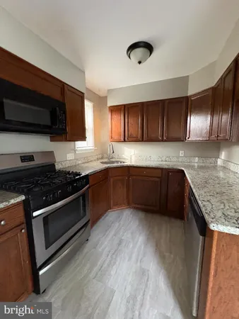 a kitchen with granite countertop a sink cabinets and stainless steel appliances