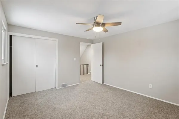 a view of an empty room and chandelier fan