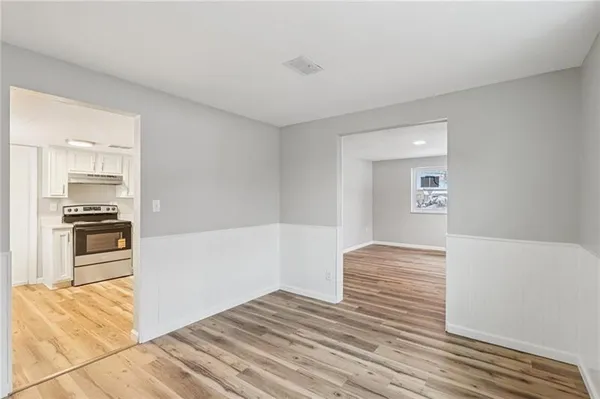 a view of kitchen and empty room with wooden floor