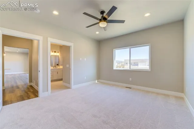 an empty room and chandelier fan and kitchen view