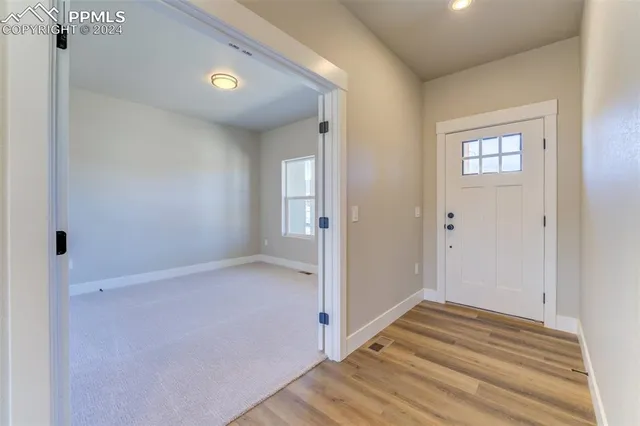 a view of a hallway with wooden floor and a bathroom