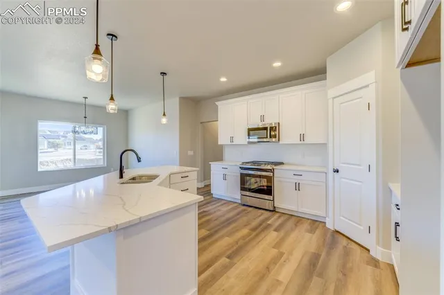 a large kitchen with stainless steel appliances a large counter top a stove a chimney a sink and a refrigerator