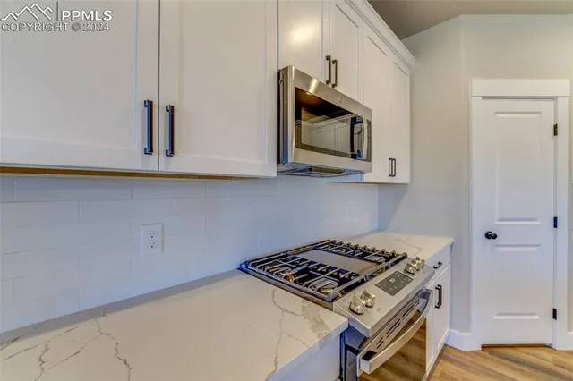 a kitchen with stainless steel appliances granite countertop white cabinets and stove