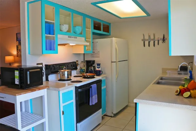 a kitchen with stainless steel appliances granite countertop a refrigerator a stove and a sink with wooden floor