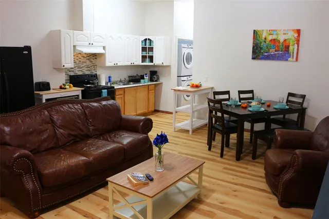 a living room with furniture and a dining table with wooden floor