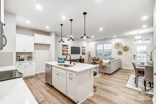 a large white kitchen with a stove a sink dishwasher and a refrigerator with wooden floor
