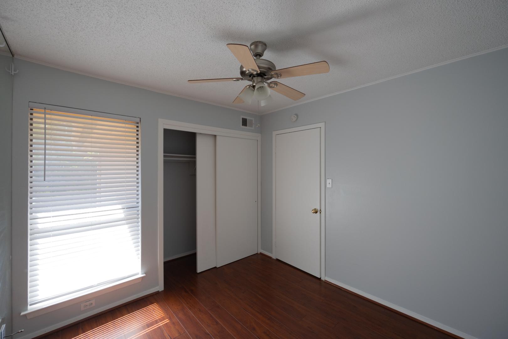 2110 Rio Grande Street, Unit 307 Austin, TX 78705 - Photo 8 of 12 Rich hardwood flooring complements a bedroom offering a ceiling fan and generous closet space.