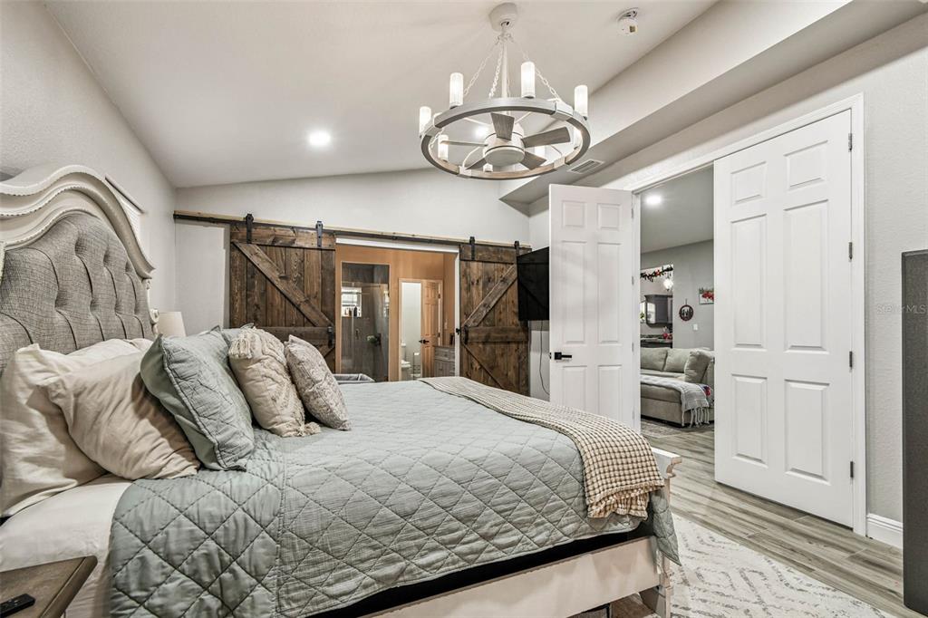 748 McClellan Road Frostproof, FL 33843 - Photo 18 of 31 a bedroom with a large bed and a chandelier