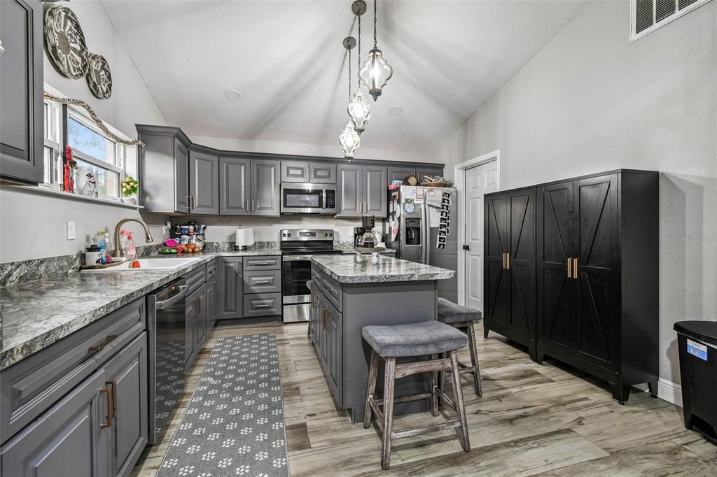 748 McClellan Road Frostproof, FL 33843 - Photo 7 of 31 a kitchen with granite countertop stainless steel appliances a sink stove and refrigerator