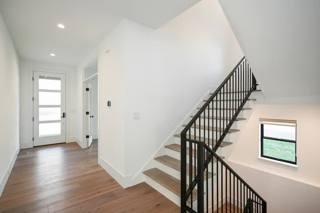 a view of a hallway with wooden floor and stairs