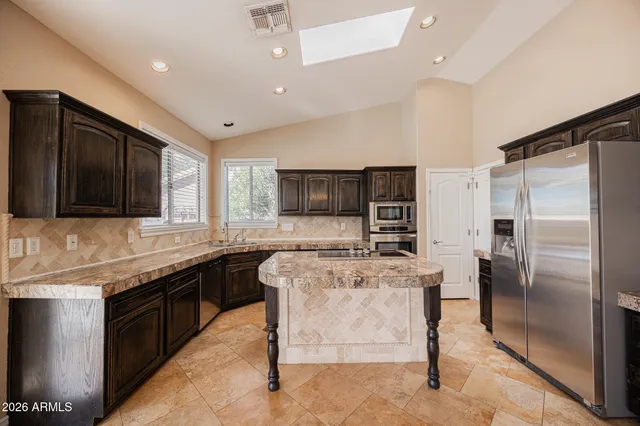 a kitchen with stainless steel appliances granite countertop sink stove refrigerator and cabinets