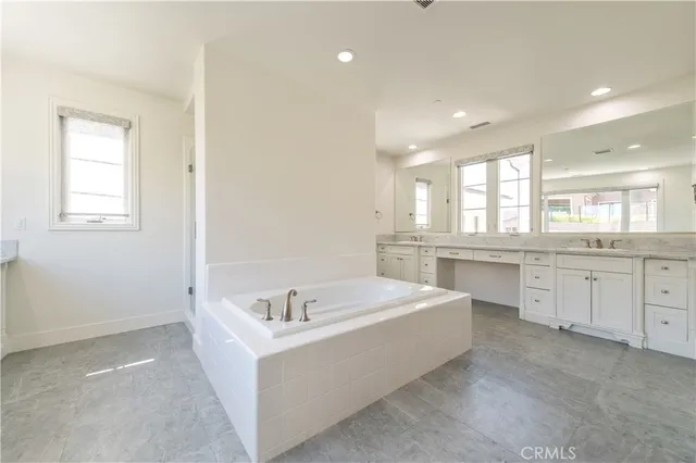 a bathroom with a granite countertop sink double and mirror bathtub