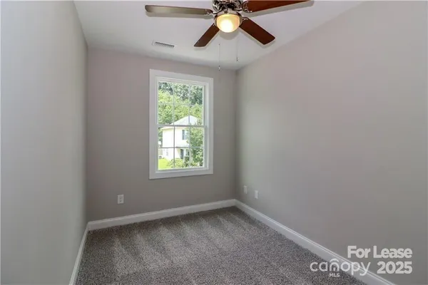 an empty room with a window and a fan