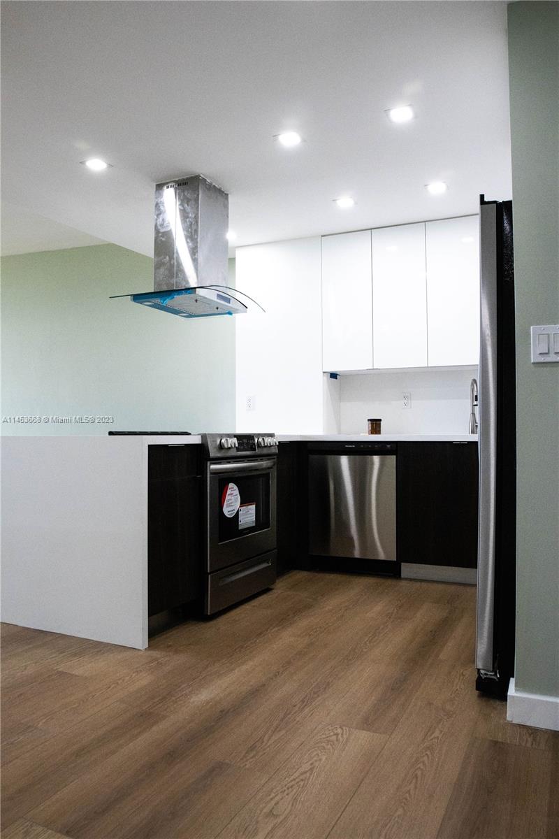 North Beach Miami Beach, FL 33141 - Photo 3 of 30 a kitchen with kitchen island stainless steel appliances a sink cabinets and wooden floor