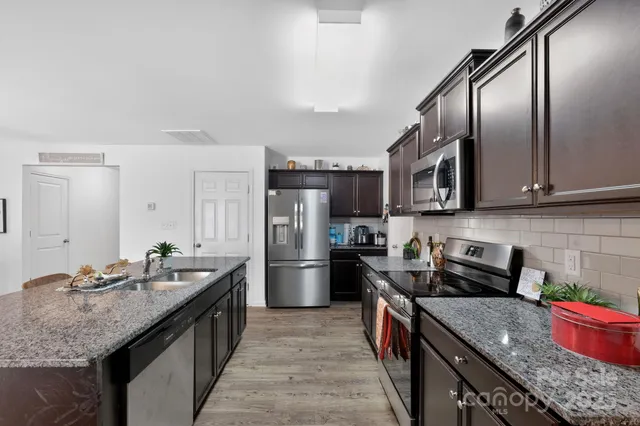 a kitchen with stainless steel appliances granite countertop a sink stove and refrigerator