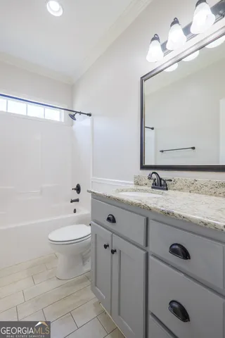 a bathroom with a granite countertop sink a toilet mirror and bathtub