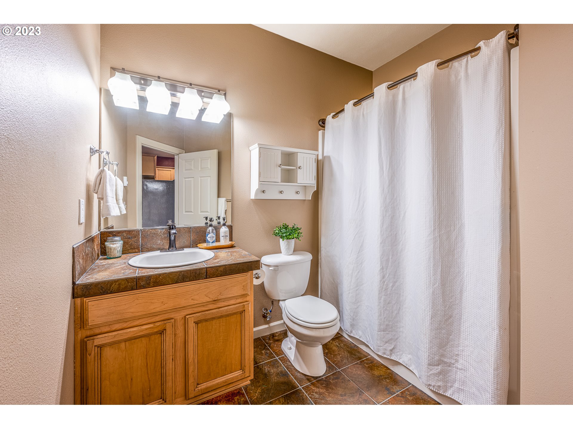 17335 Ruben Lane, Unit 19 Sandy, OR 97055 - Photo 17 of 27 a bathroom with a granite countertop sink a toilet a mirror and shower curtain