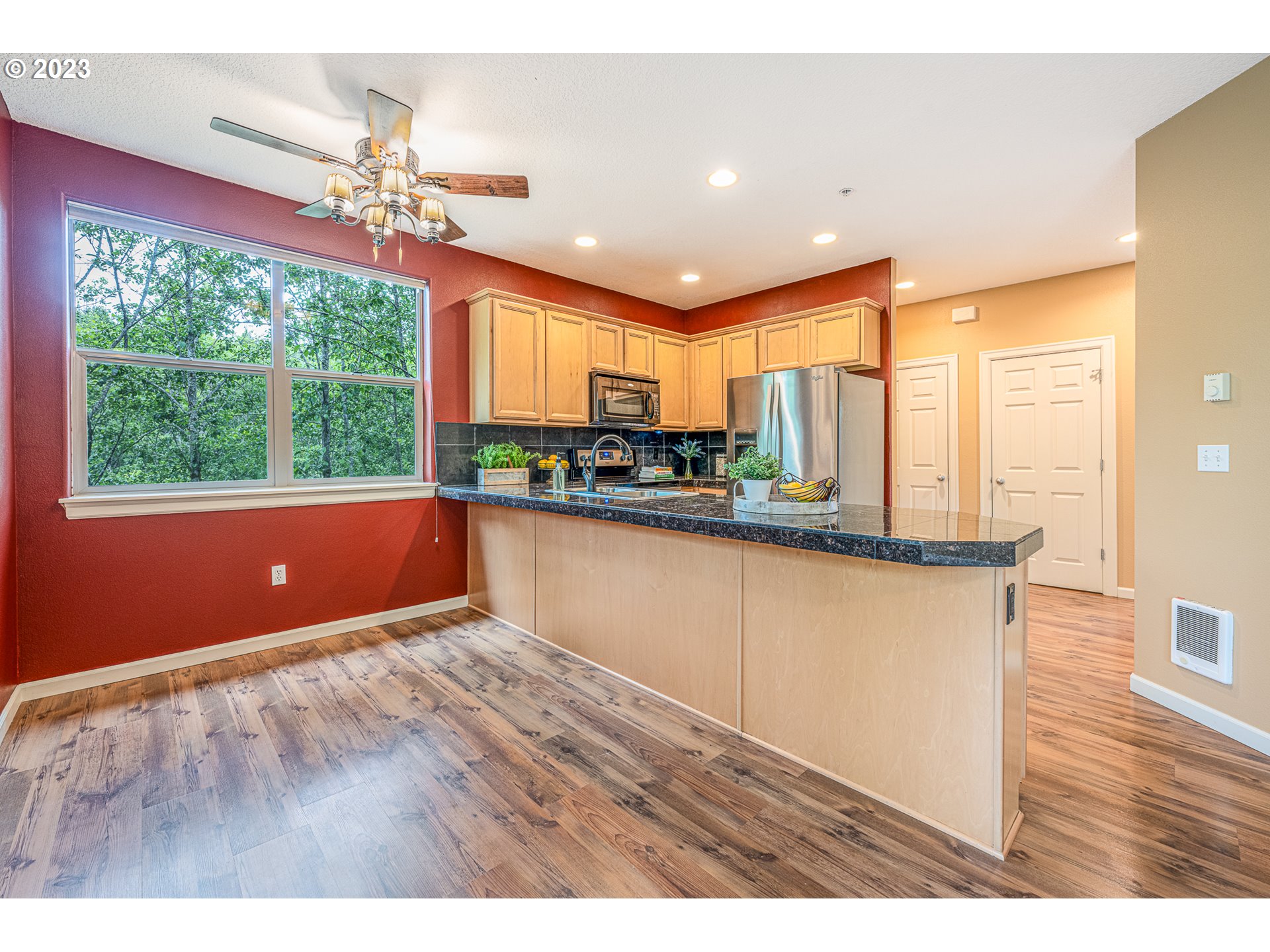 17335 Ruben Lane, Unit 19 Sandy, OR 97055 - Photo 4 of 27 a kitchen with stainless steel appliances granite countertop a refrigerator a stove top oven a large window with wooden floor and outdoor view