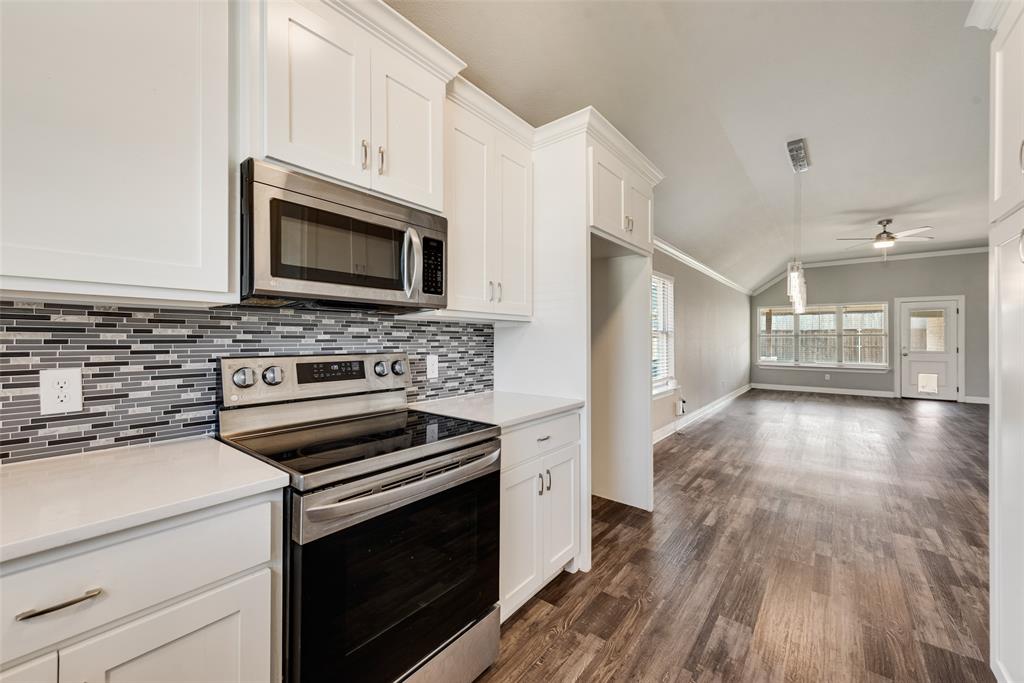 625 Copenhavr Street Pilot Point, TX 76258 - Photo 7 of 20 Kitchen featuring stainless steel appliances, white cabinetry, ceiling fan, dark wood-style flooring, and vaulted ceiling
