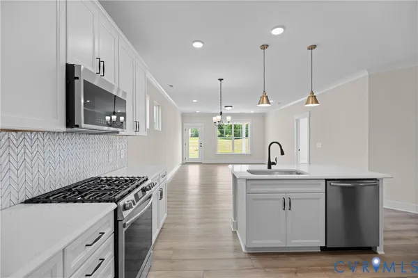 a kitchen with stainless steel appliances granite countertop a sink a stove and a wooden floors