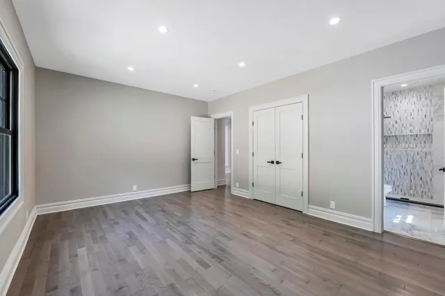 a view of an empty room with wooden floor and closet