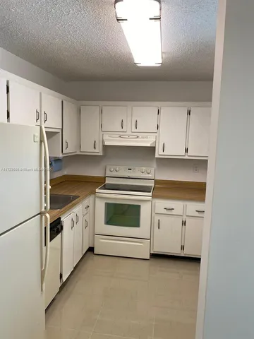 a kitchen with granite countertop white cabinets and white stainless steel appliances