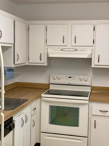 a kitchen with white cabinets and appliances