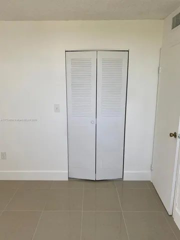 an empty room with windows and chandelier fan