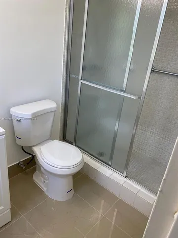 a white toilet sitting next to a shower