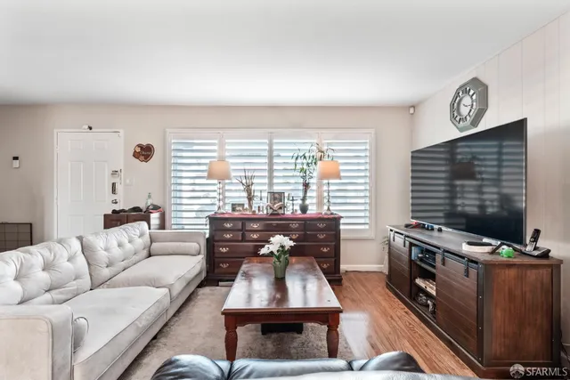 a living room with furniture a flat screen tv and a window