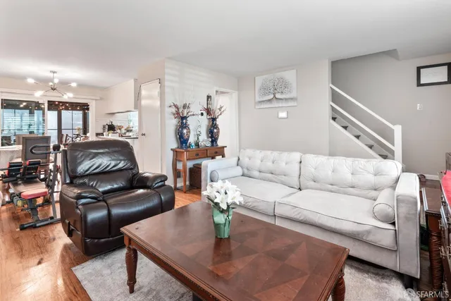 a living room with furniture and a dining table with wooden floor