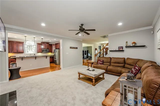 a living room with furniture kitchen view and a wooden floor