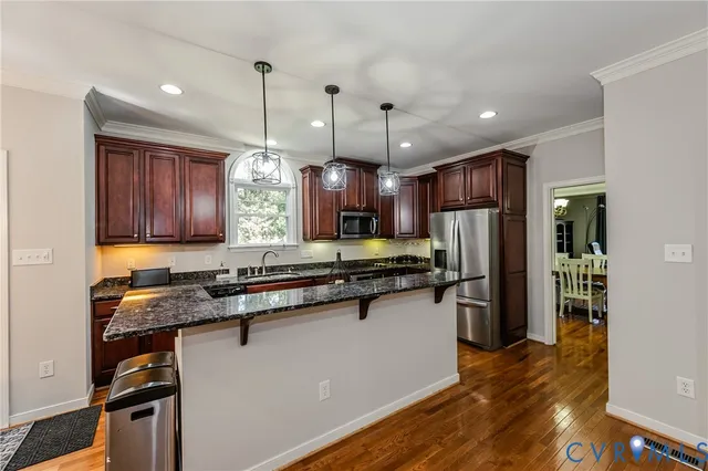 a kitchen with stainless steel appliances granite countertop a refrigerator a sink dishwasher a stove and white countertops with wooden floor