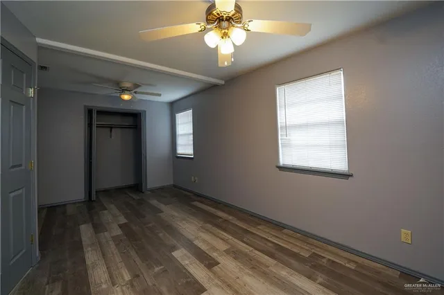 a view of a room with wooden floor and a ceiling fan