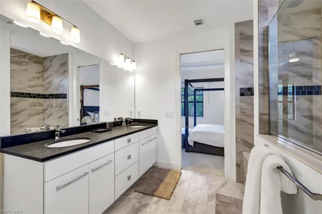 a spacious en suite bathroom with a granite countertop sink and a mirror