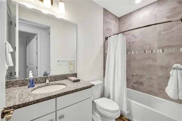 a bathroom with a granite countertop sink toilet and shower