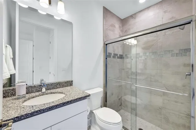 a bathroom with a granite countertop sink toilet and shower