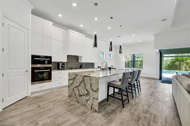 a kitchen with stainless steel appliances kitchen island granite countertop a stove a sink a dining table and chairs