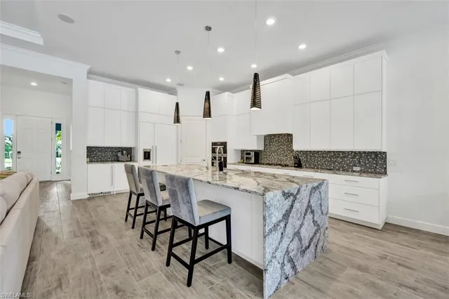 a kitchen with stainless steel appliances kitchen island granite countertop a table chairs sink and cabinets