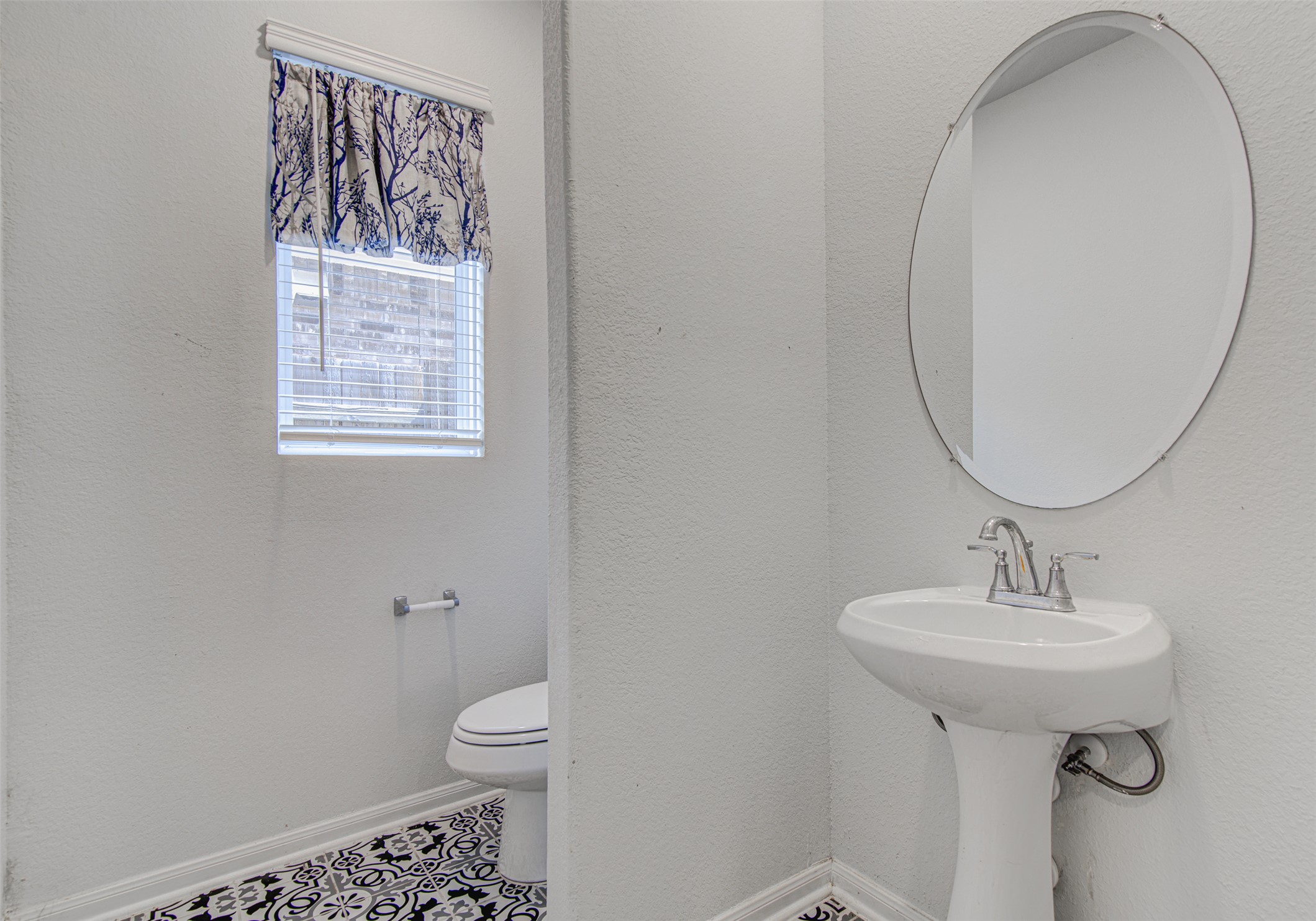 774 Cherrystone Loop Buda, TX 78610 - Photo 12 of 38 A compact and functional bathroom features a modern pedestal sink paired with a sleek oval mirror.